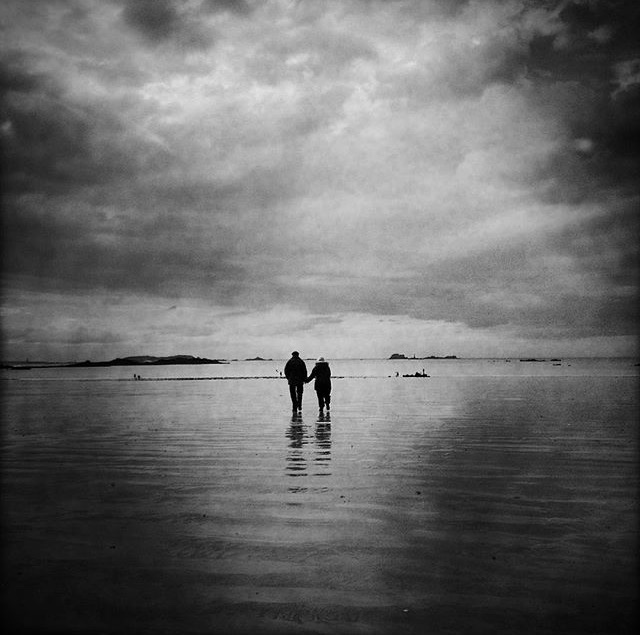 The couple on the beach, Saint-Malo, Brittany. This elderly couple, hand in hand, were walking together to the sea, to the same horizon. A single moment of great beauty and complicity.