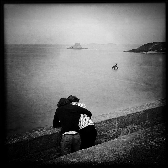 Lovers, Saint-Malo, Brittany. At high tide, alone, entwined, these two lovers enjoyed a quiet moment and the beautiful view of the horizon. By the sea, solo, as a couple, in family or just among friends, we look and allow our mind to wander.